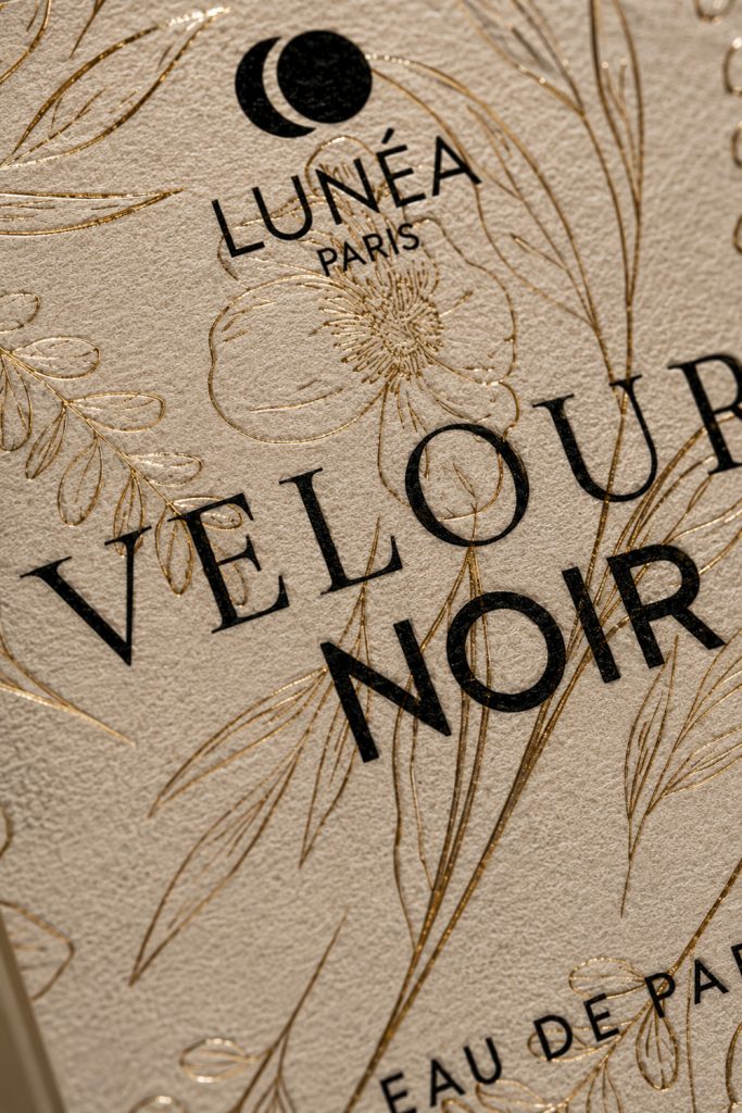Détail de l'étiquette du parfum Velours Noir avec dorure et texture papier premium