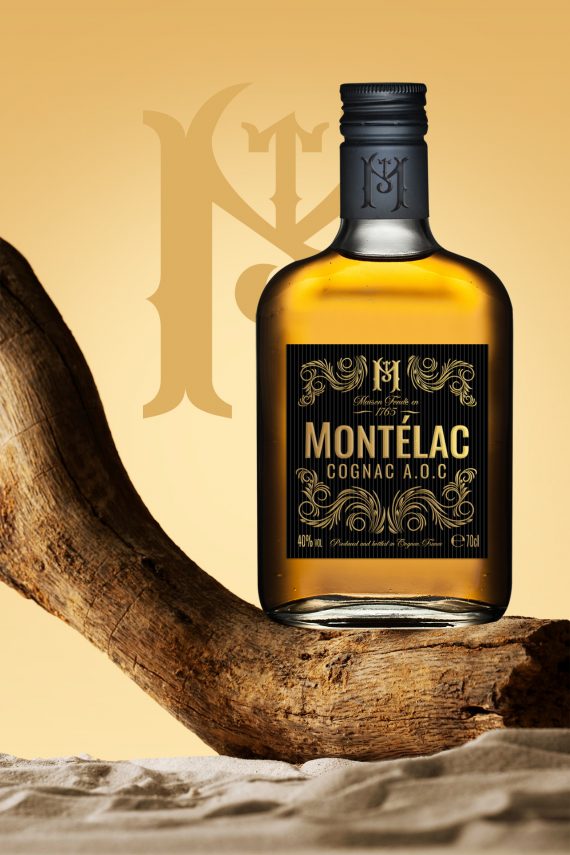 Packaging pour vins et spiritueux haut de gamme – bouteille de Cognac Montélac posée sur un fond bois et sable, design premium