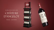 Totem PLV de sol pour vin Château d’Angelot en Pessac-Léognan, présentoir noir premium avec bouteilles et visuel de la cuvée sur fond rouge élégant