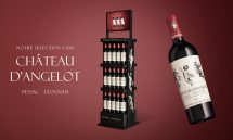 Totem PLV de sol pour vin Château d’Angelot en Pessac-Léognan, présentoir noir premium avec bouteilles et visuel de la cuvée sur fond rouge élégant