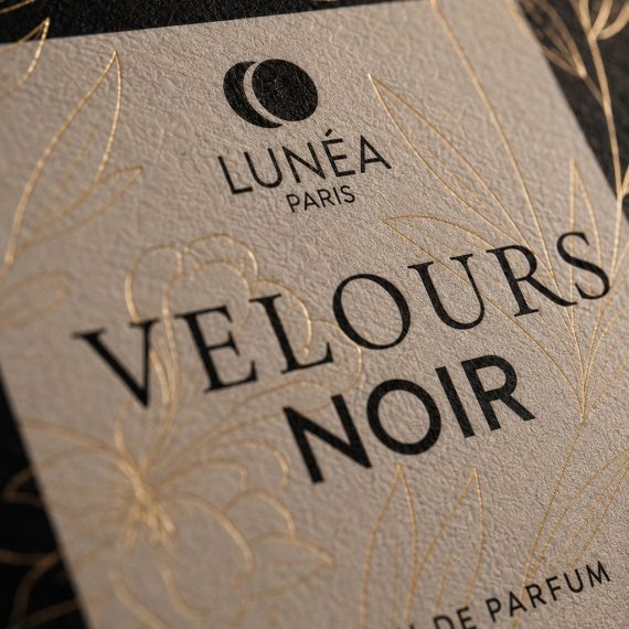 Gros plan sur les finitions du coffret Velours Noir avec dorure à chaud, texture du papier et design de packaging parfum haut de gamme.
