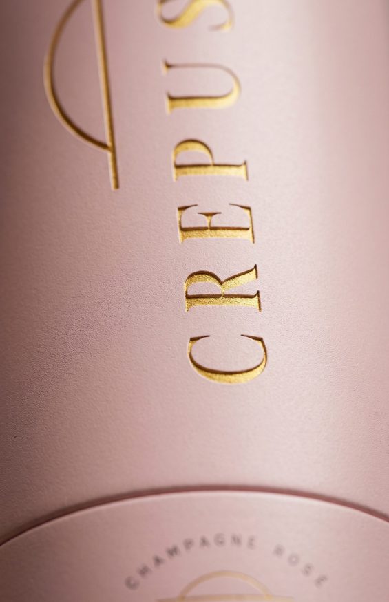 Zoom macro sur les détails dorés et la texture du coffret champagne Crépuscule dans un univers packaging luxe contemporain.