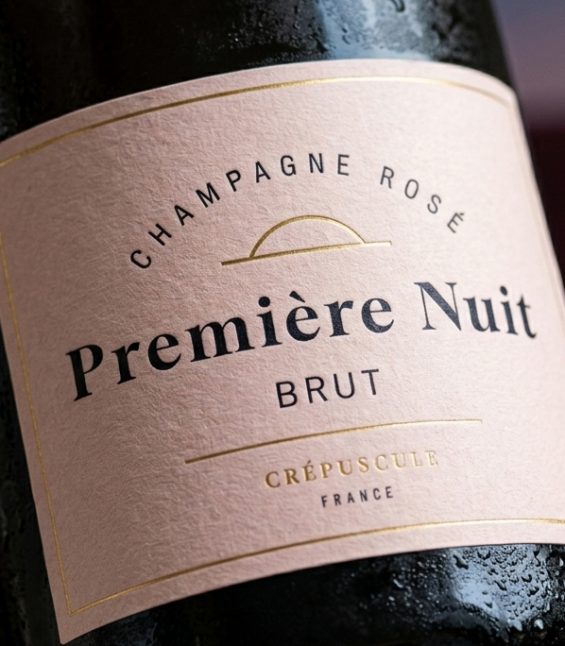 Gros plan sur l’étiquette texturée du champagne rosé Première Nuit avec finitions dorées et typographie premium minimaliste conçue pour la marque Crépuscule.